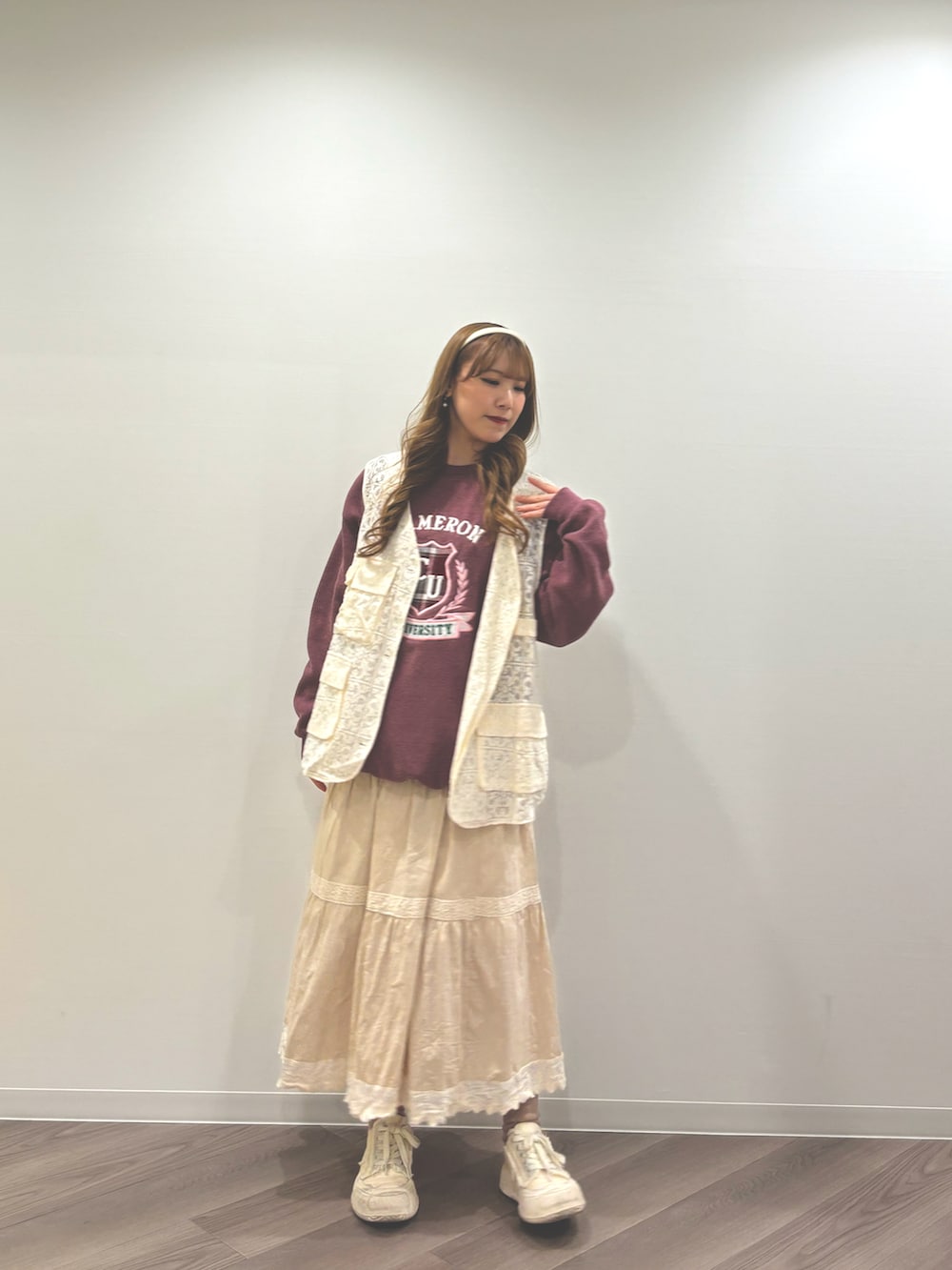 ホワイト系のスニーカー、ベージュ系のスカート、ホワイト系のベストを着用したレディースの冬コーディネートの2枚目の写真