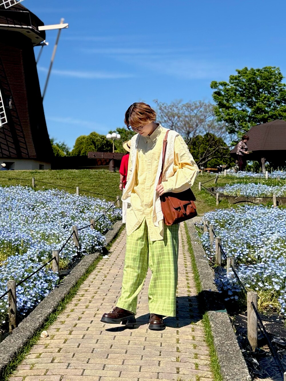 ホワイト系のベスト、グリーン系のその他パンツ、イエロー系のショルダーバッグを着用したレディースの春コーディネートの3枚目の写真