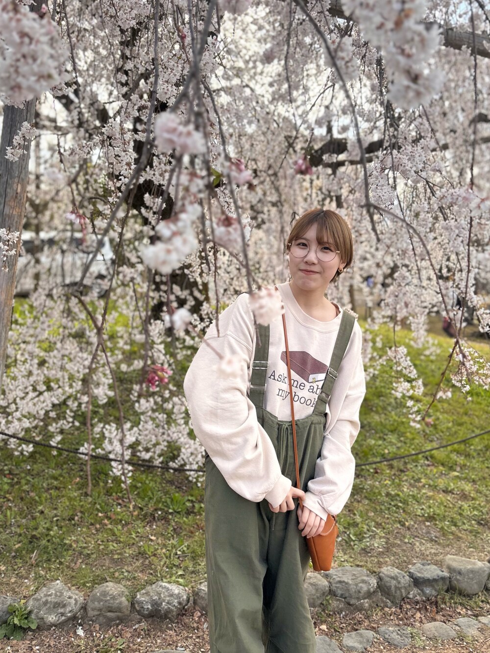 ベージュ系のスウェット、グリーン系のオールインワン・サロペット、ブラウン系のローファーを着用したレディースの春コーディネートの3枚目の写真