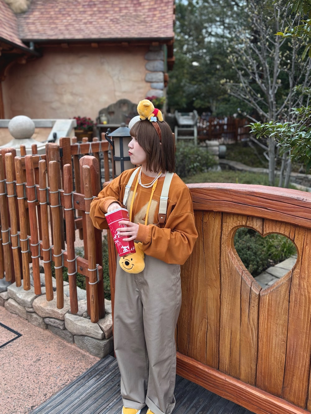 ベージュ系のチノパンツ、オレンジ系のスウェット、ホワイト系のネックレスを着用したレディースの春コーディネートの3枚目の写真