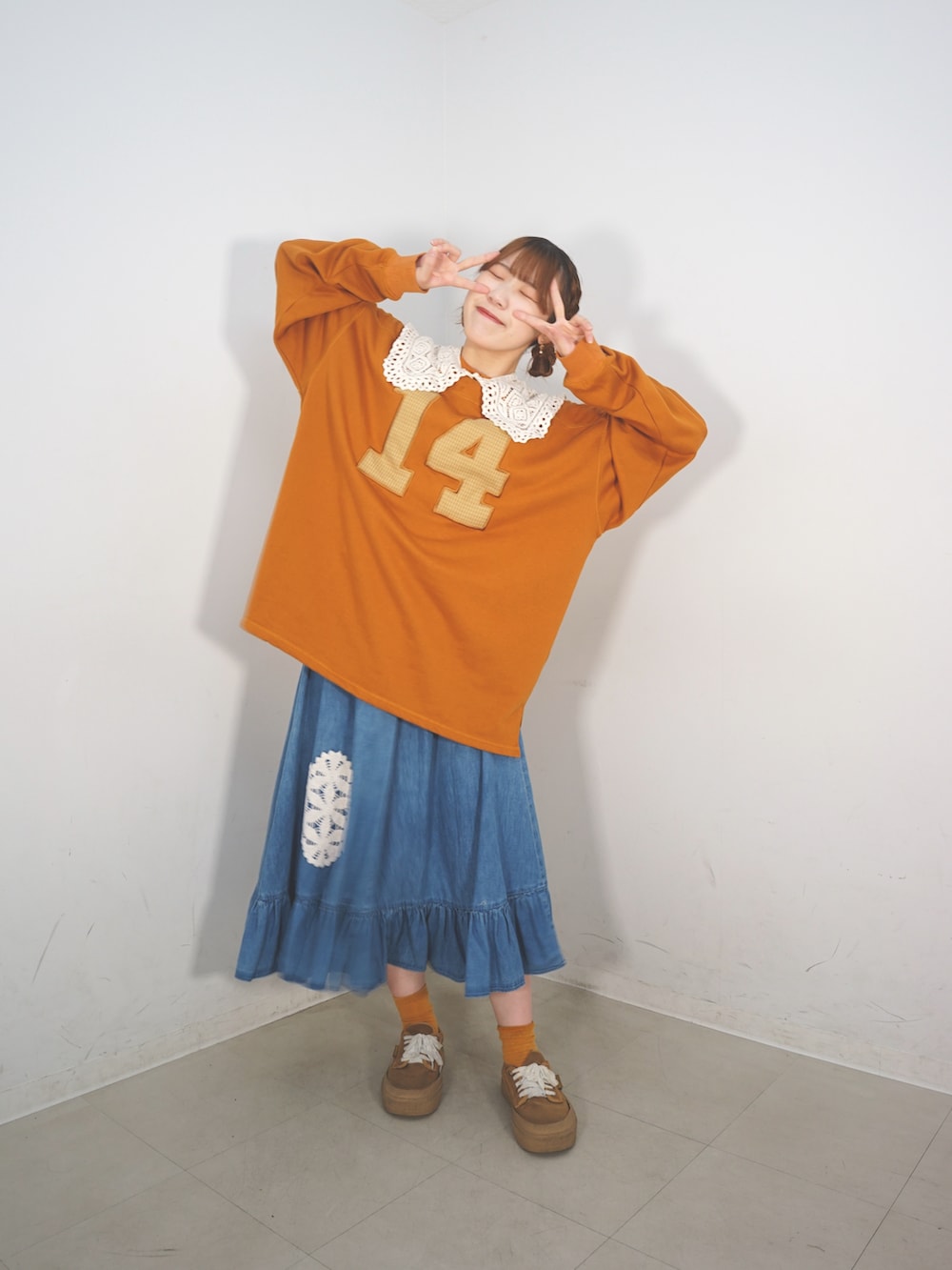 オレンジ系のスウェット、ベージュ系のスカート、ブラウン系のシューズを着用したレディースの冬コーディネートの4枚目の写真