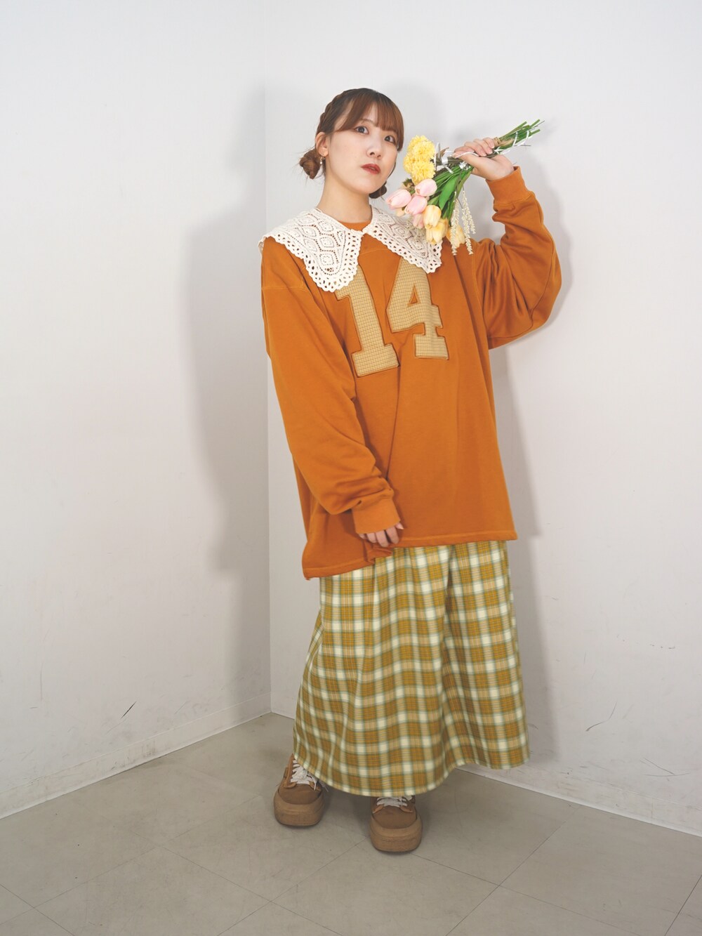 オレンジ系のスウェット、ベージュ系のスカート、ブラウン系のシューズを着用したレディースの冬コーディネートの3枚目の写真