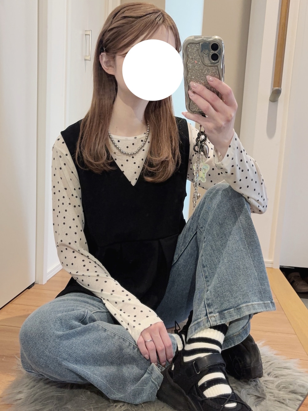 ブラック系のパーカー、ブラック系のベスト、ブルー系のデニムパンツを着用したレディースの春コーディネートの2枚目の写真