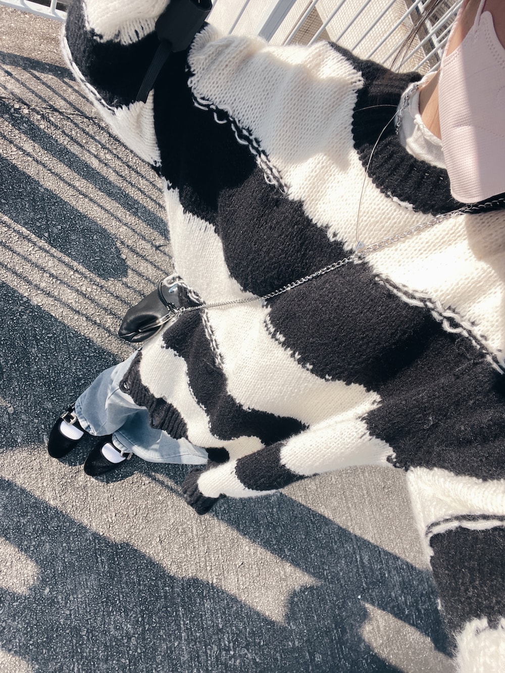 ホワイト系のバレエシューズ、ブラック系のショルダーバッグ、ブルー系のデニムパンツを着用したレディースの冬コーディネートの2枚目の写真