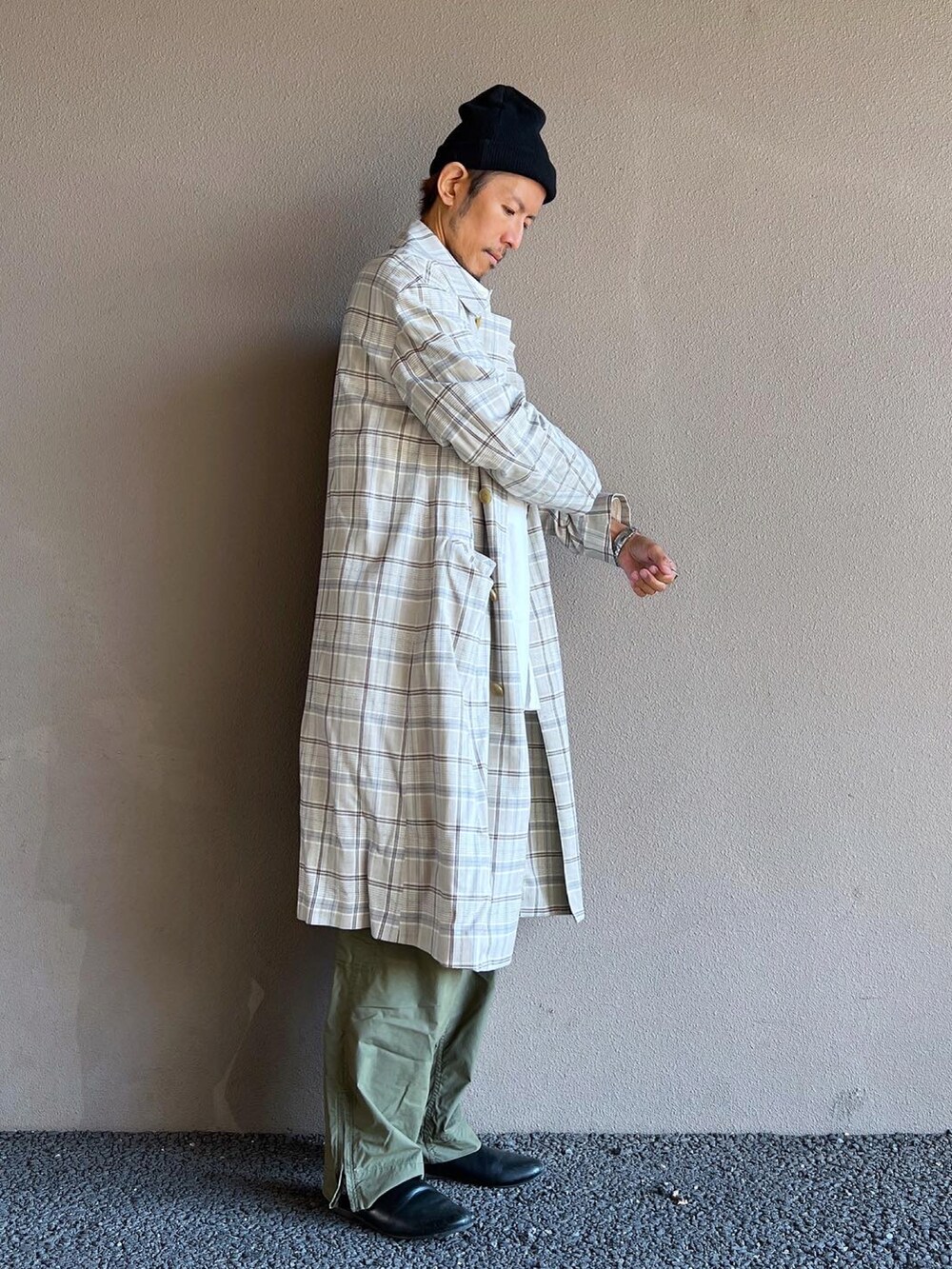 グレー系のステンカラーコート、グリーン系のカーゴパンツ、ブラック系のシューズを着用したメンズの秋コーディネートの2枚目の写真