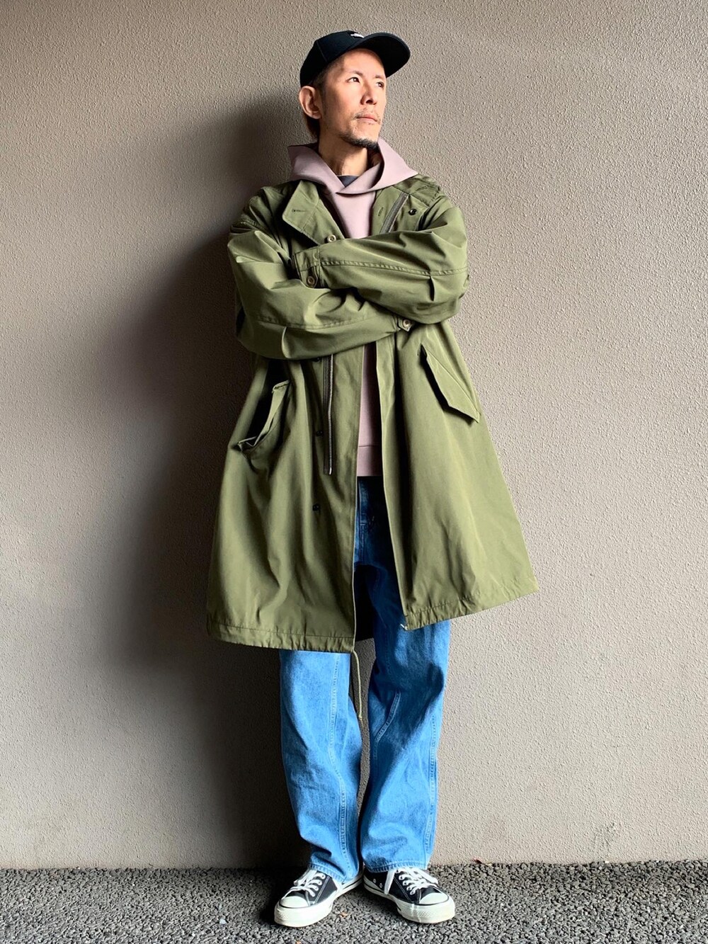 グリーン系のモッズコート、ブルー系のデニムパンツ、ブラック系のスニーカーを着用したメンズの秋コーディネートの2枚目の写真