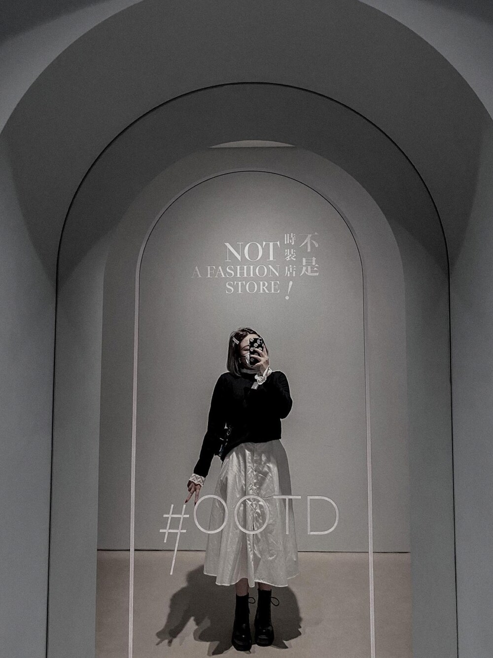 ブラック系のショルダーバッグ、ホワイト系のスカート、ブラック系のブーツを着用したレディースの冬コーディネートの2枚目の写真