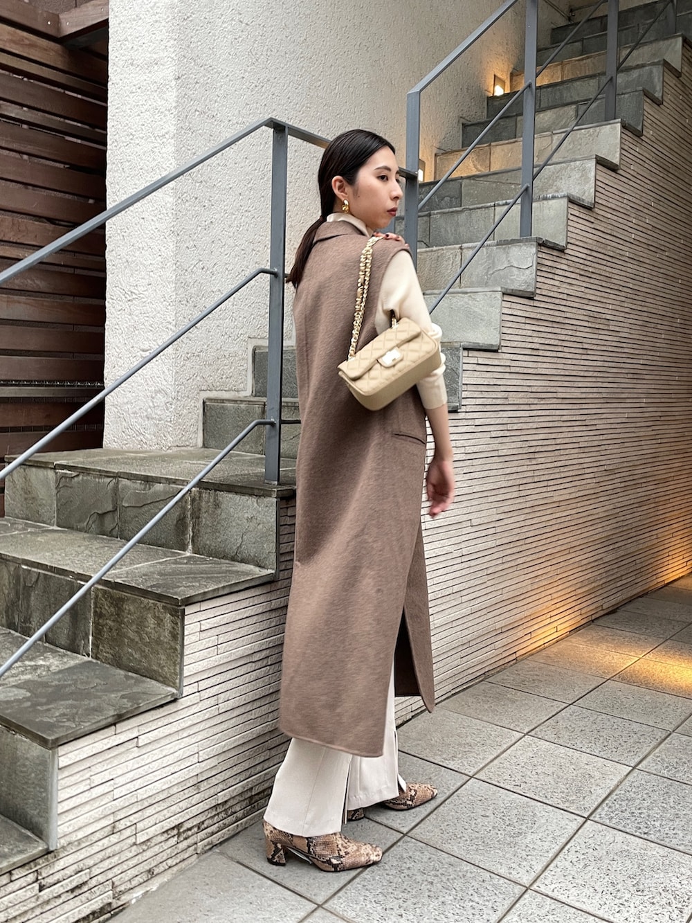 ベージュ系のトップス、ブラウン系のその他アウター、ホワイト系のスラックスを着用したレディースの秋コーディネートの2枚目の写真