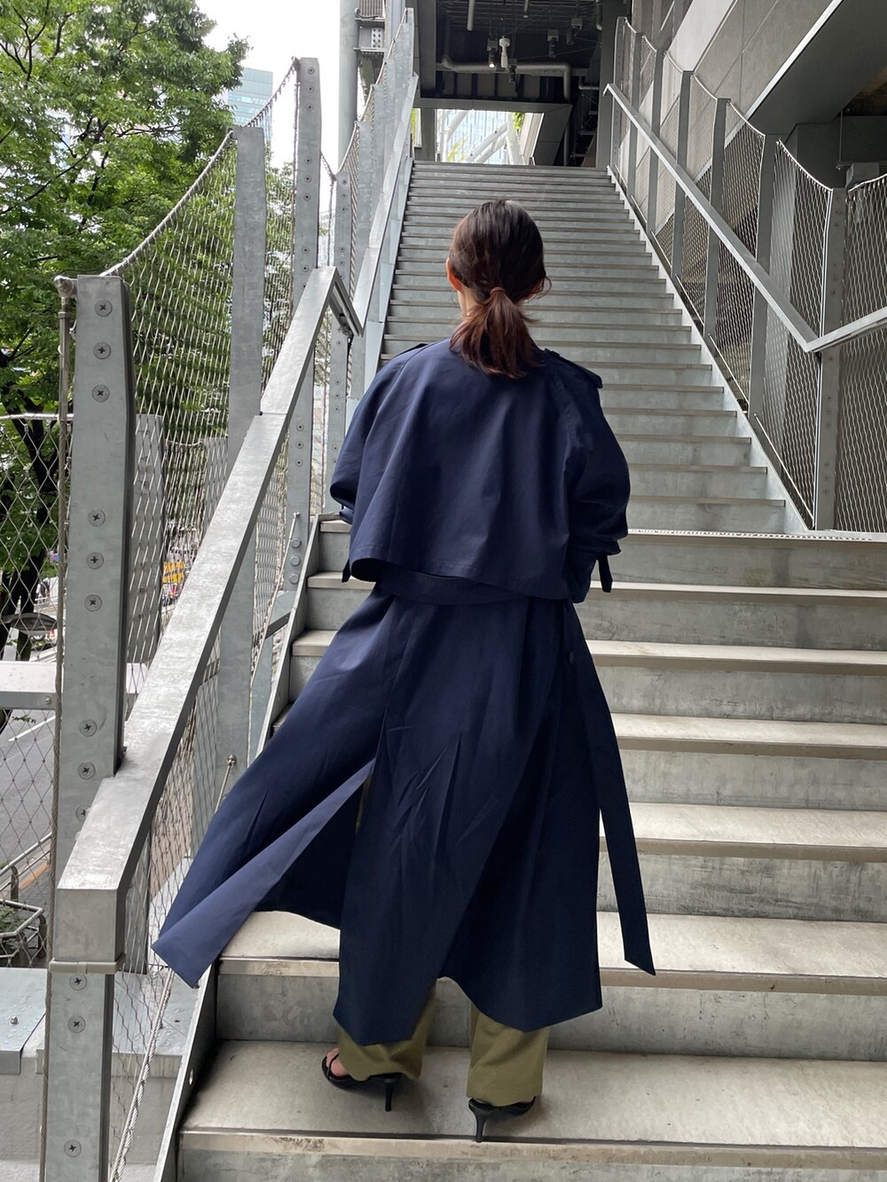 ブルー系のトレンチコート、ブラック系のTシャツ/カットソー、グリーン系のカーゴパンツを着用したレディースの夏コーディネートの2枚目の写真