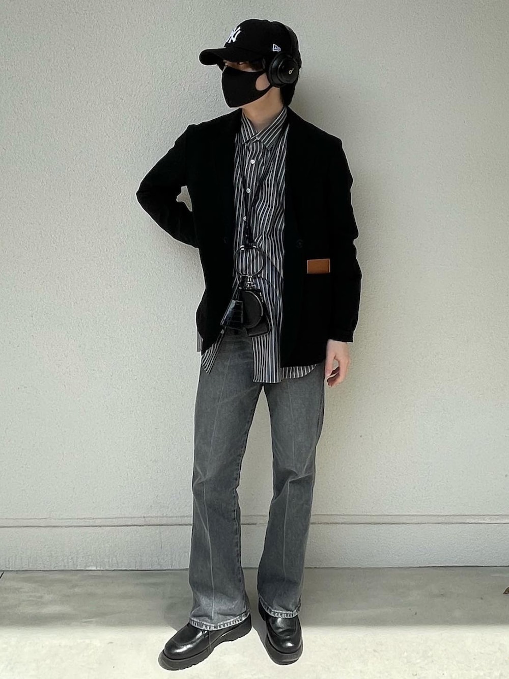 ブルー系のデニムパンツ、ブラック系のドレスシューズ、ブラック系のショルダーバッグを着用したメンズの春コーディネートの4枚目の写真