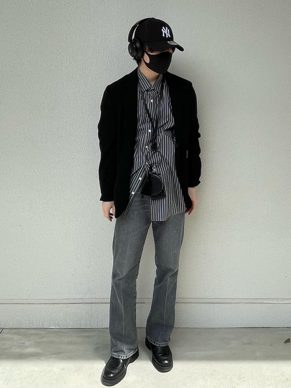 ブルー系のデニムパンツ、ブラック系のドレスシューズ、ブラック系のショルダーバッグを着用したメンズの春コーディネートの5枚目の写真