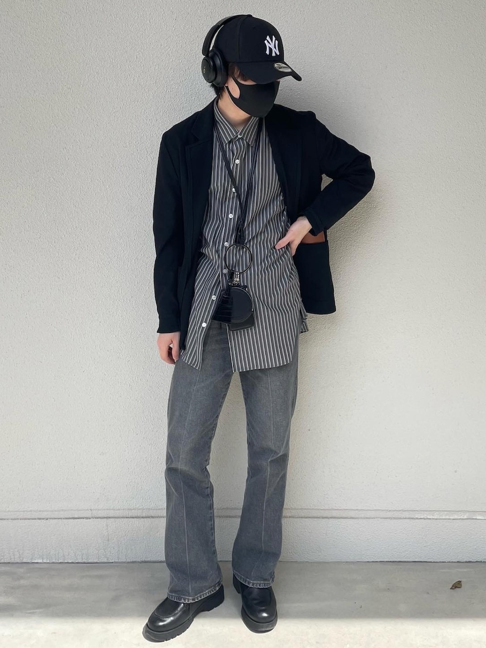 ブルー系のデニムパンツ、ブラック系のドレスシューズ、ブラック系のショルダーバッグを着用したメンズの春コーディネートの2枚目の写真