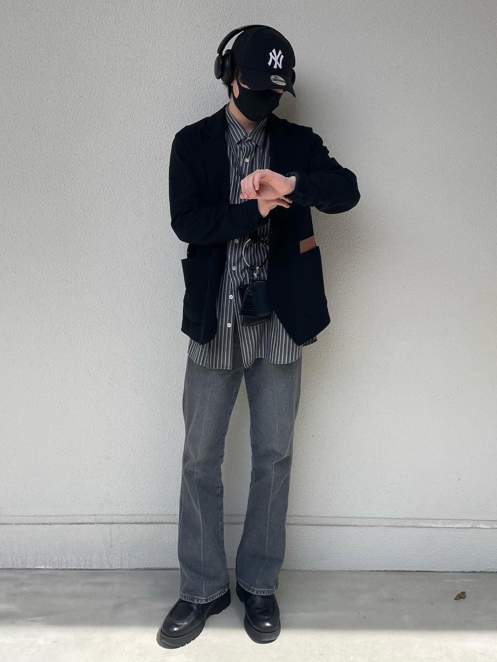 ブルー系のデニムパンツ、ブラック系のドレスシューズ、ブラック系のショルダーバッグを着用したメンズの春コーディネートの3枚目の写真