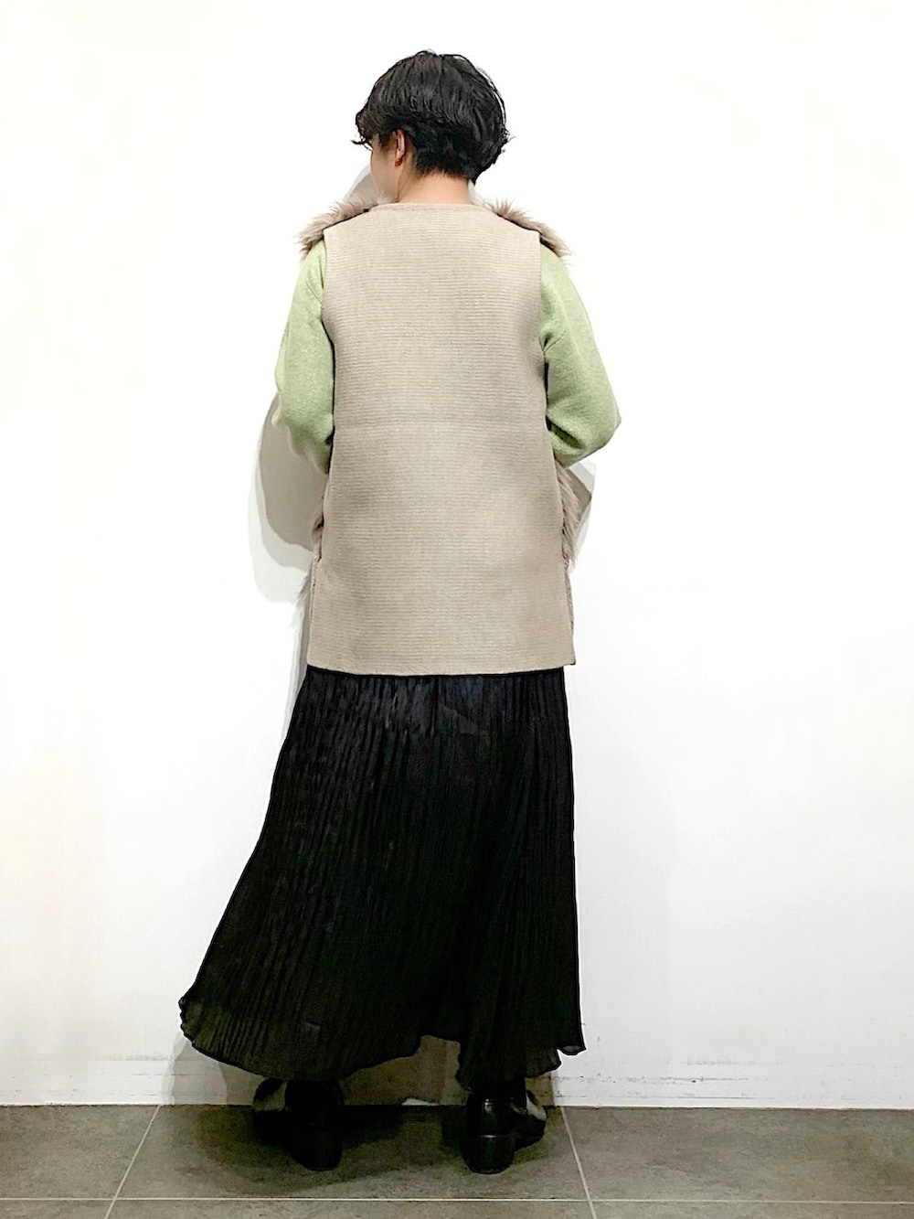 ブラック系のブーツ、ブラック系のスカート、グリーン系のニット/セーターを着用したレディースの秋コーディネートの3枚目の写真