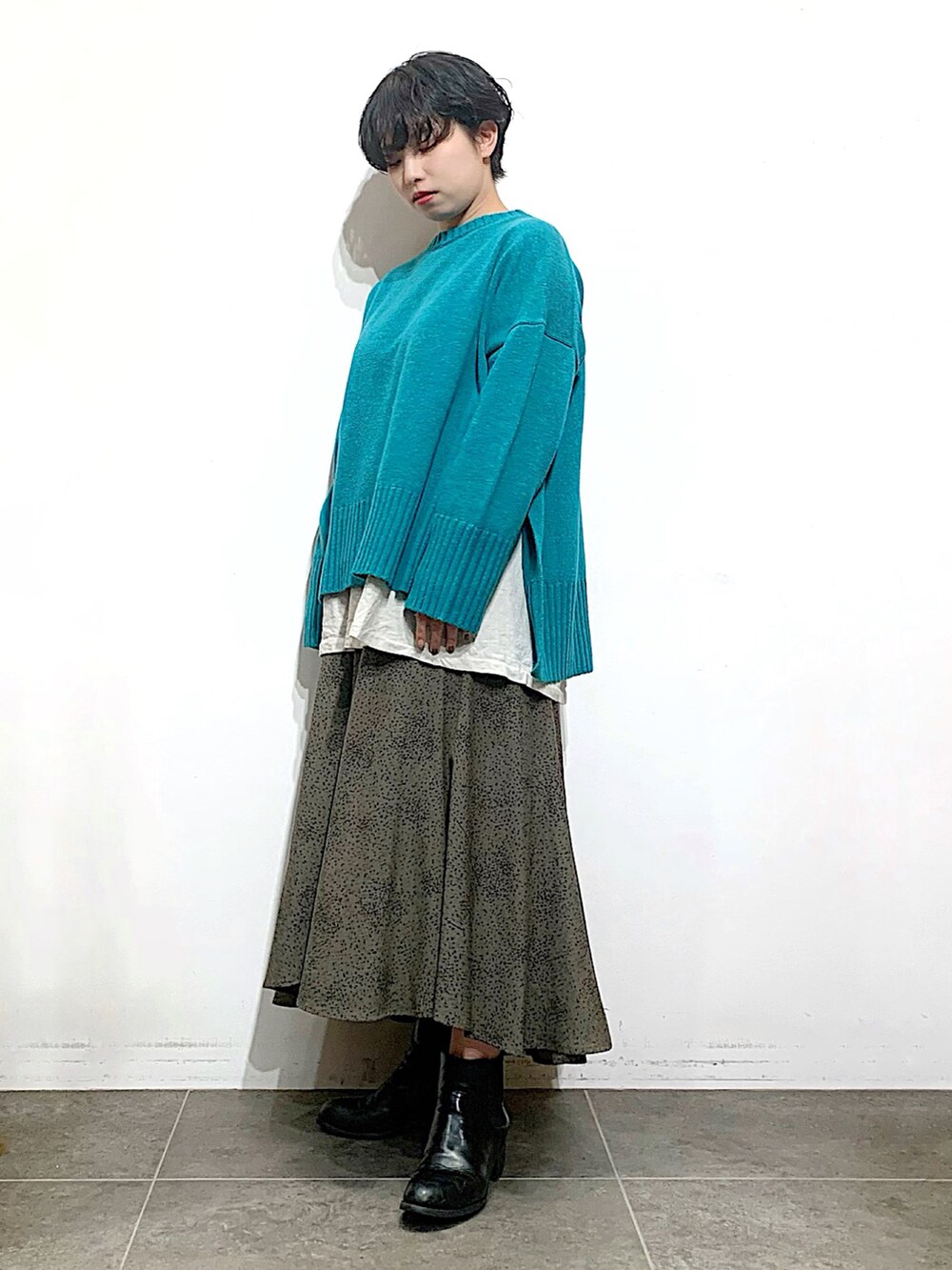ブラック系のブーツ、グレー系のスカート、グリーン系のニット/セーターを着用したレディースの秋コーディネートの2枚目の写真