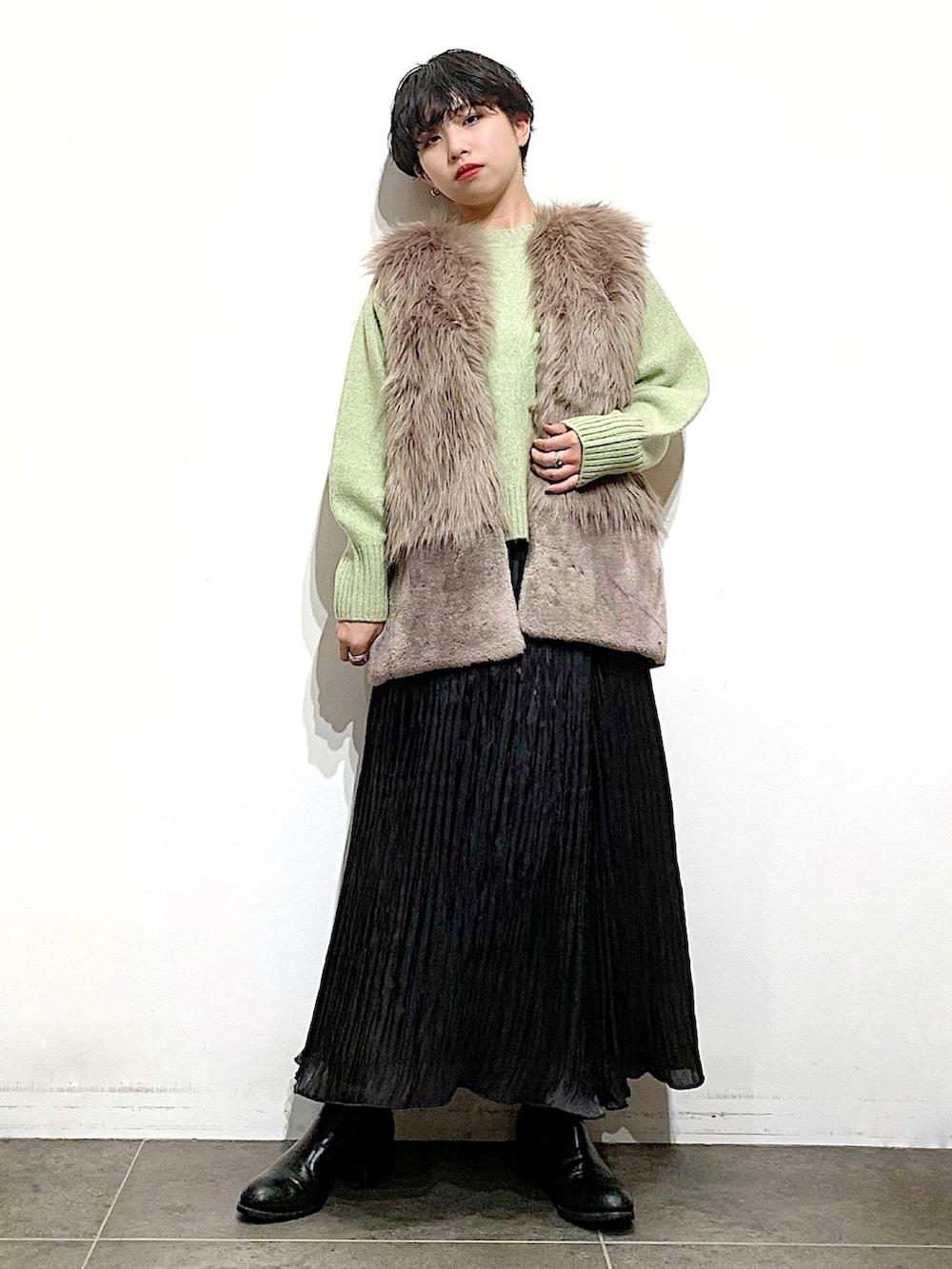 ブラック系のブーツ、ブラック系のスカート、グリーン系のニット/セーターを着用したレディースの秋コーディネートの2枚目の写真