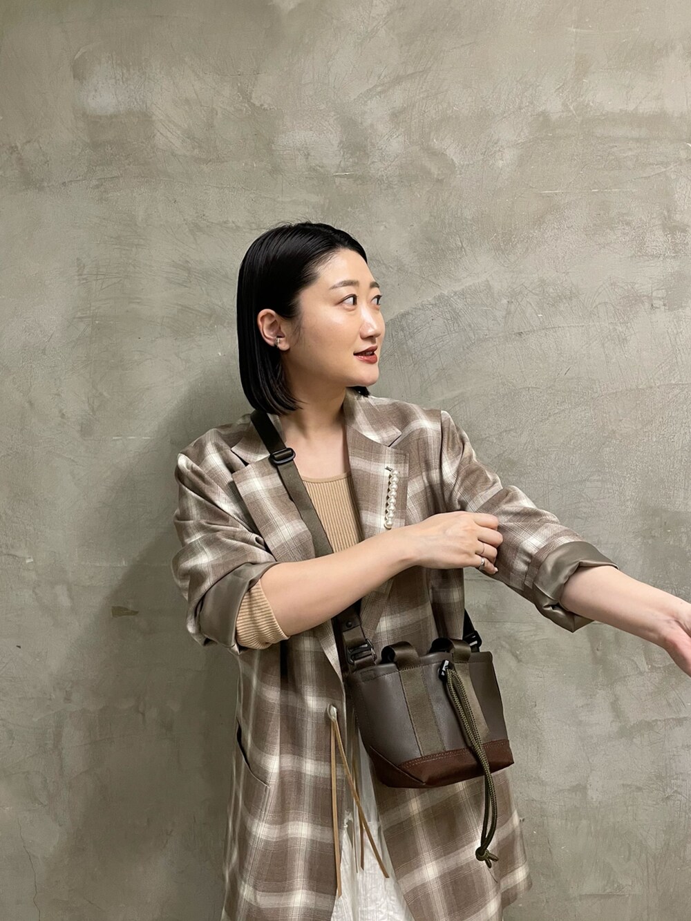 ベージュ系のニット/セーター、ブラウン系のトートバッグ、ブラック系のスニーカーを着用したレディースの春コーディネートの4枚目の写真