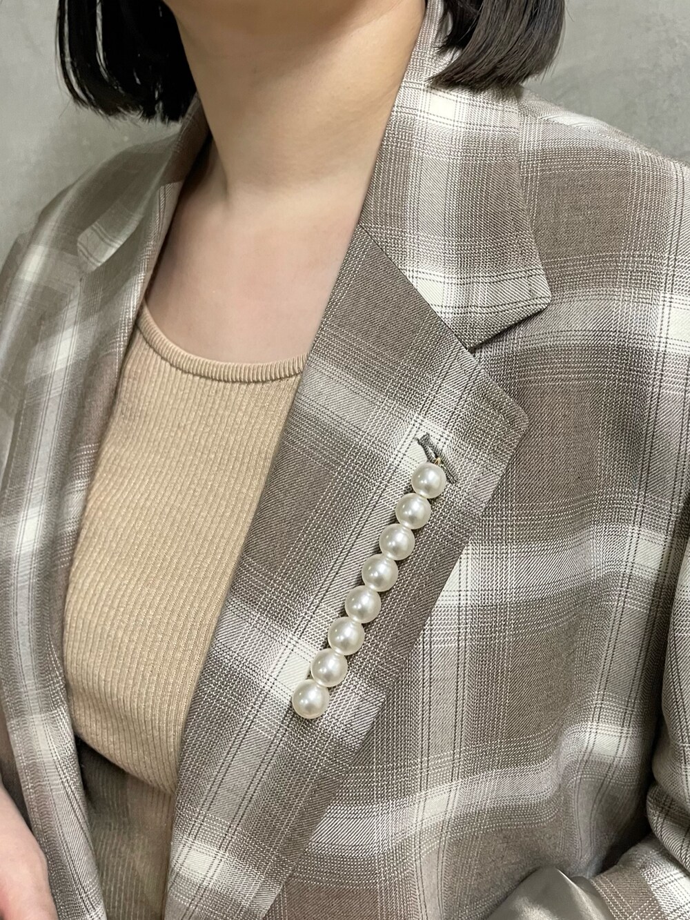 ベージュ系のニット/セーター、ブラウン系のトートバッグ、ブラック系のスニーカーを着用したレディースの春コーディネートの8枚目の写真