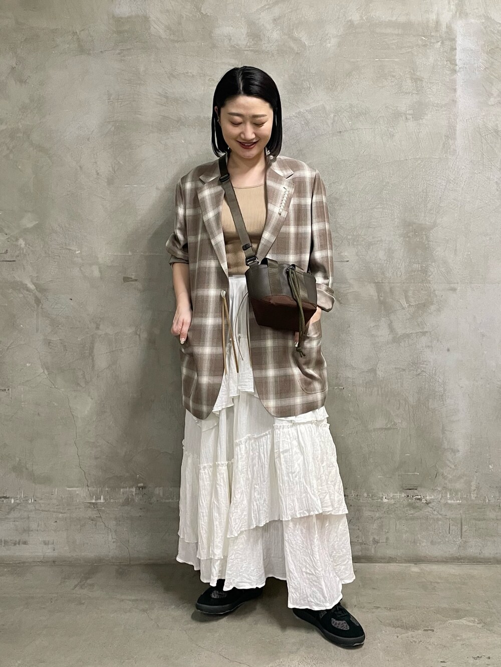 ベージュ系のニット/セーター、ブラウン系のトートバッグ、ブラック系のスニーカーを着用したレディースの春コーディネートの2枚目の写真