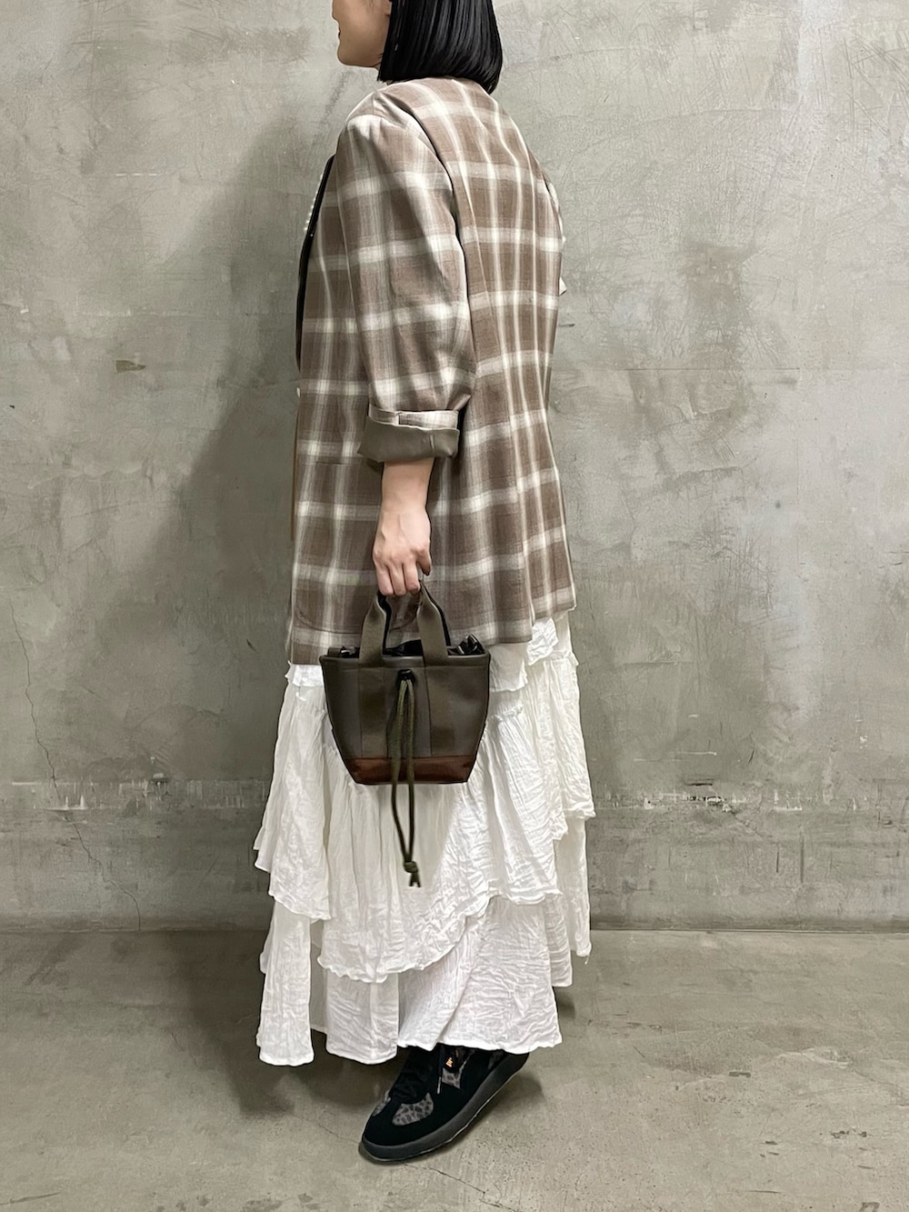 ベージュ系のニット/セーター、ブラウン系のトートバッグ、ブラック系のスニーカーを着用したレディースの春コーディネートの3枚目の写真