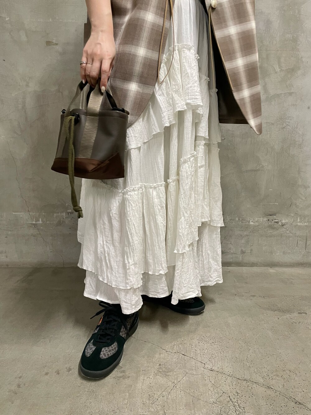 ベージュ系のニット/セーター、ブラウン系のトートバッグ、ブラック系のスニーカーを着用したレディースの春コーディネートの5枚目の写真