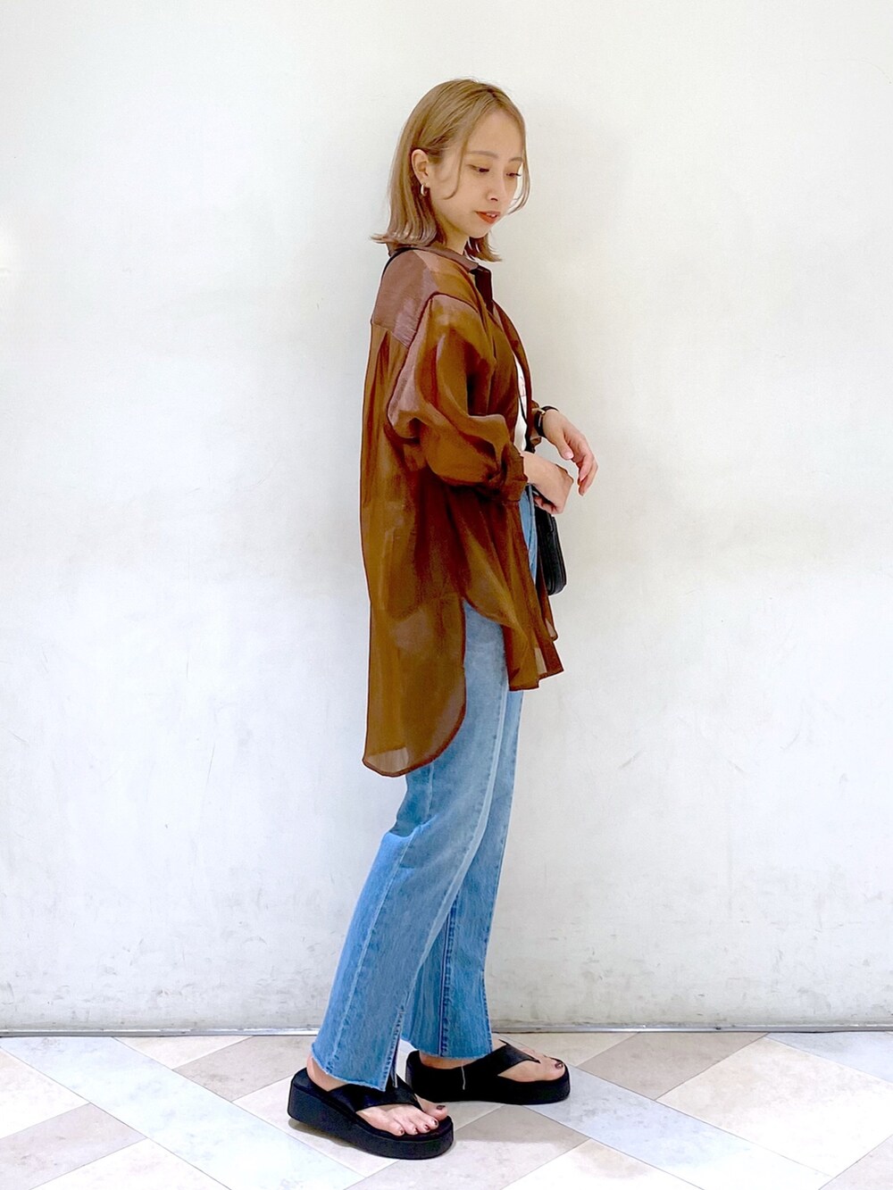 ブラック系のショルダーバッグ、ブラック系のサンダル、ブルー系のデニムパンツを着用したレディースの夏コーディネートの2枚目の写真