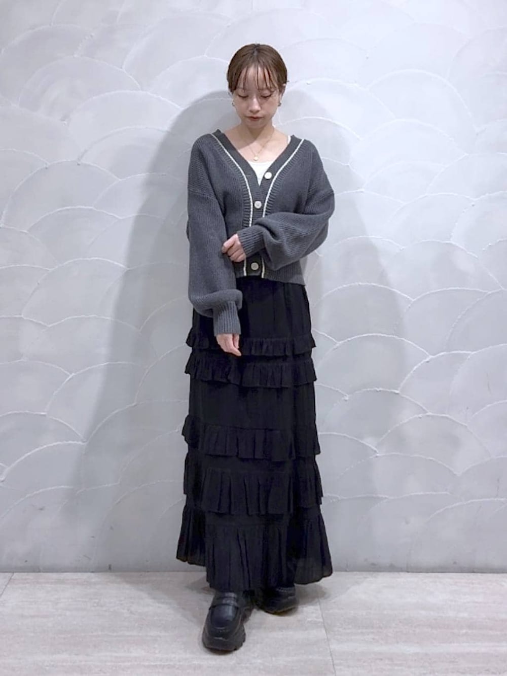 ホワイト系のTシャツ/カットソー、グレー系のカーディガン/ボレロ、ブラック系のローファーを着用したレディースの冬コーディネートの2枚目の写真