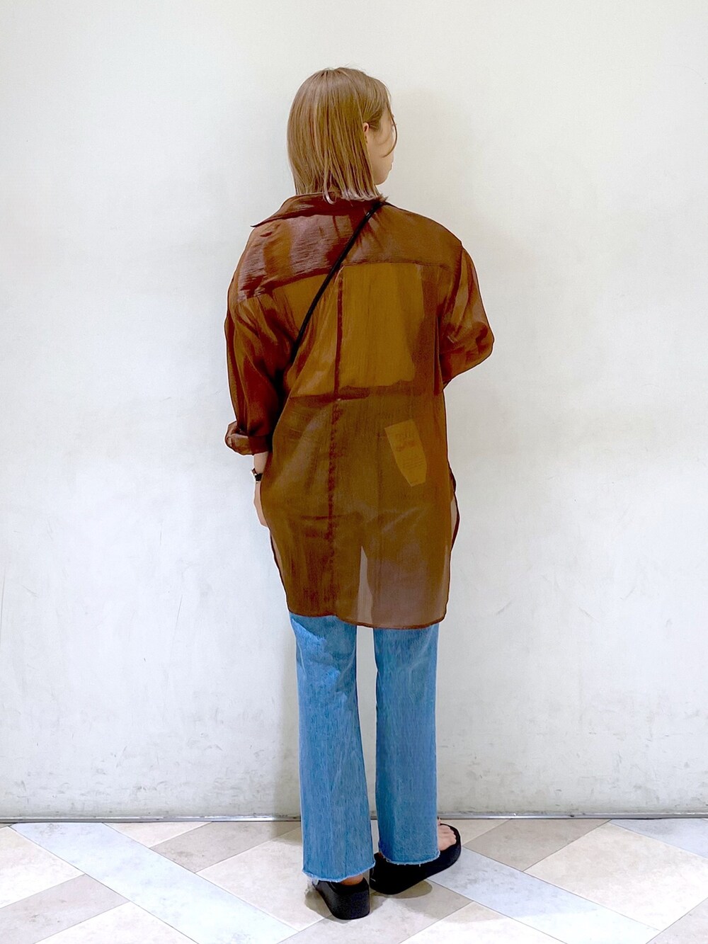 ブラック系のショルダーバッグ、ブラック系のサンダル、ブルー系のデニムパンツを着用したレディースの夏コーディネートの3枚目の写真