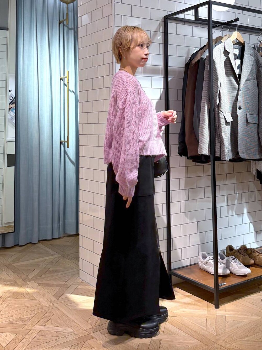 ブラック系のブーツ、ブラック系のショルダーバッグ、ブラック系のスカートを着用したレディースの秋コーディネートの3枚目の写真