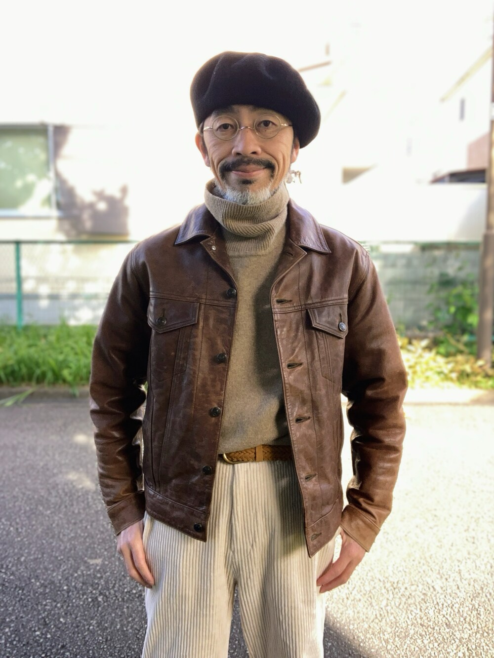 ブラウン系のライダースジャケット、ベージュ系のニット/セーター、ホワイト系のパンツを着用したメンズの秋コーディネートの4枚目の写真