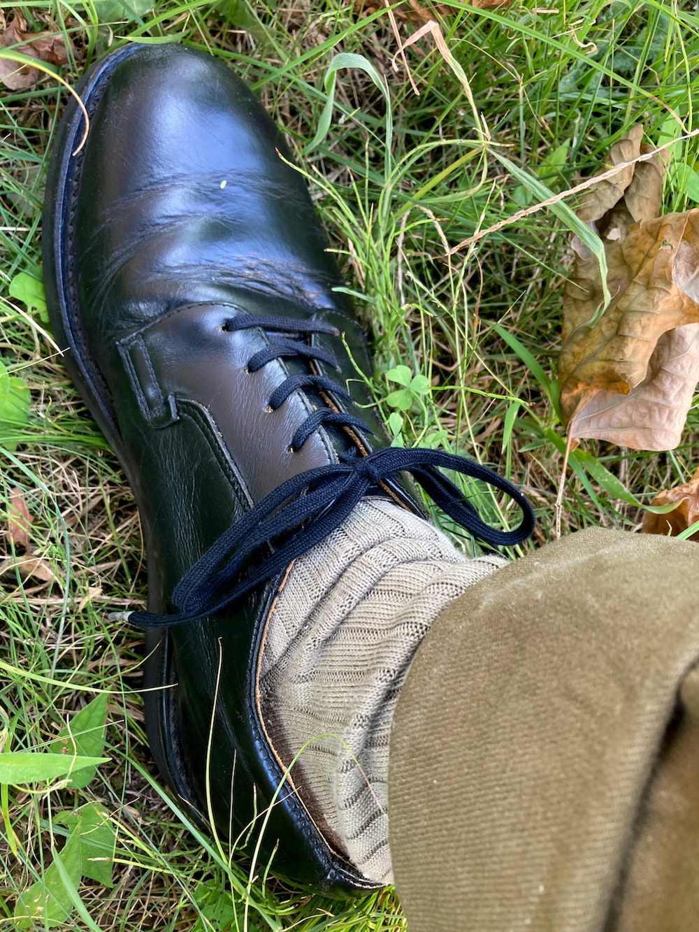 ホワイト系のTシャツ/カットソー、グリーン系のスラックス、ブラック系のドレスシューズを着用したメンズの夏コーディネートの3枚目の写真