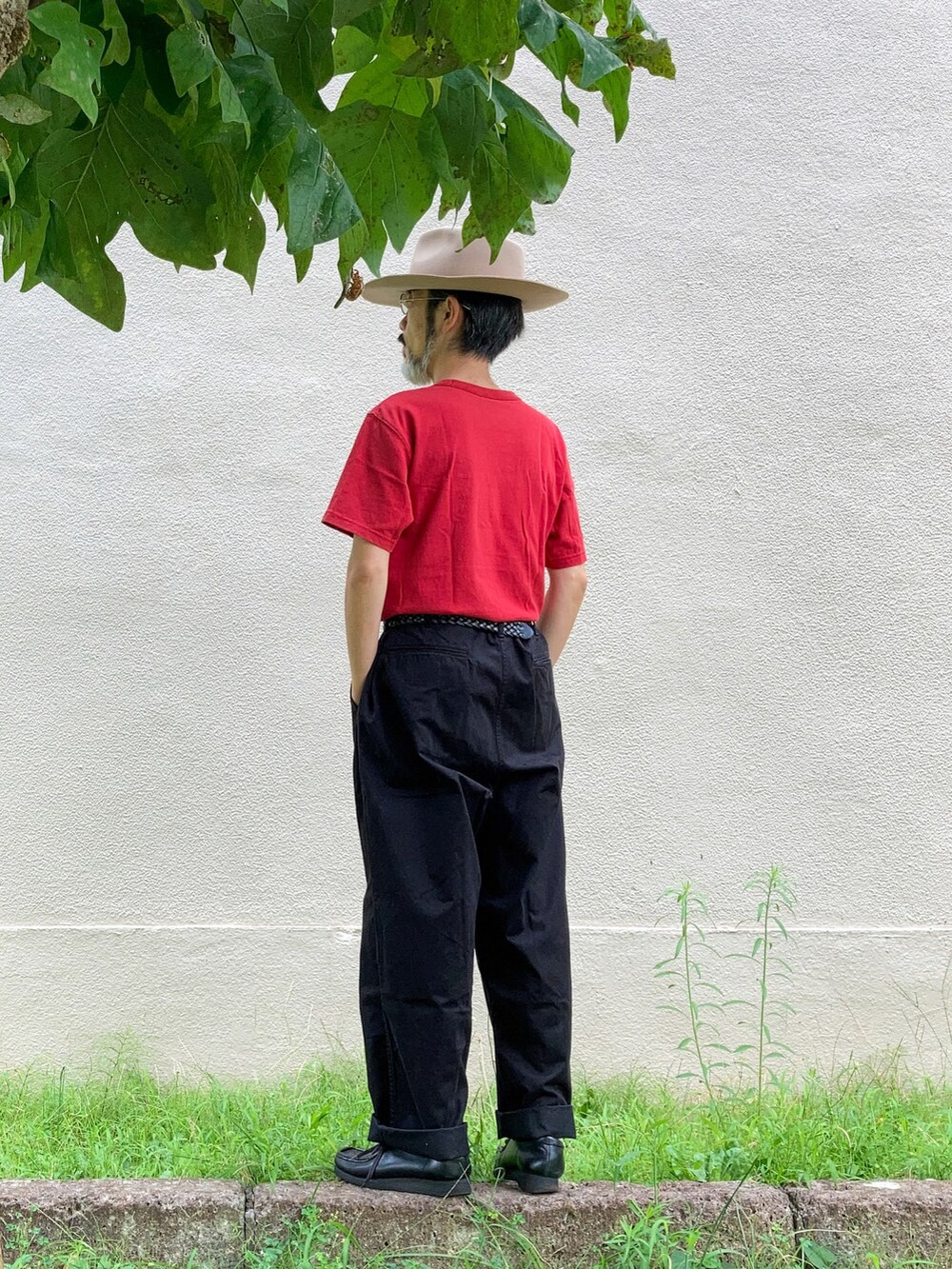 レッド系のTシャツ/カットソー、ブラック系のチノパンツ、ブラック系のモカシン/デッキシューズを着用したメンズの夏コーディネートの2枚目の写真