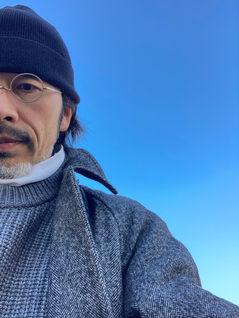 ホワイト系のTシャツ/カットソー、グレー系のニット/セーター、グレー系のステンカラーコートを着用したメンズの冬コーディネートの5枚目の写真