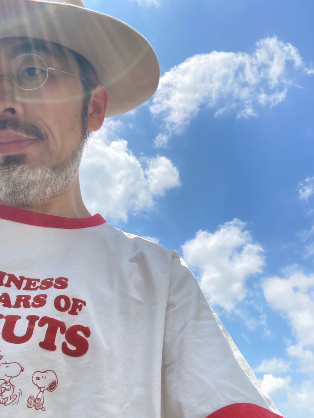 ブラック系のデニムパンツ、ブラック系のブーツ、ホワイト系のTシャツ/カットソーを着用したメンズの夏コーディネートの4枚目の写真