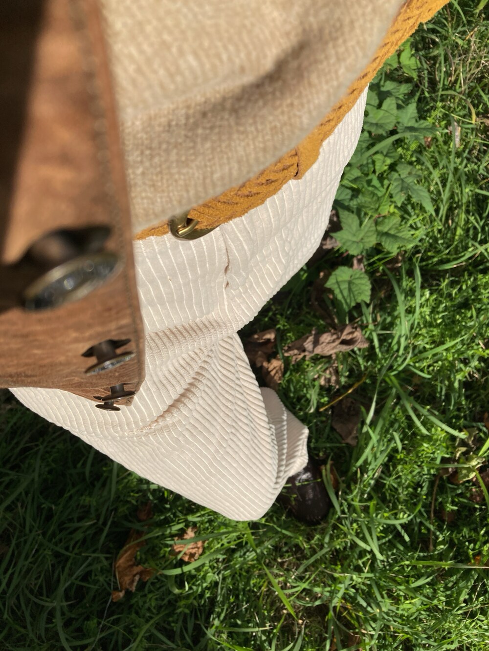 ブラウン系のライダースジャケット、ベージュ系のニット/セーター、ホワイト系のパンツを着用したメンズの秋コーディネートの2枚目の写真