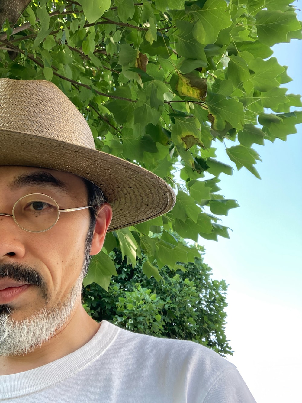 ホワイト系のTシャツ/カットソー、グリーン系のスラックス、ブラック系のドレスシューズを着用したメンズの夏コーディネートの4枚目の写真