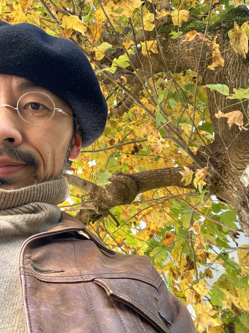 ブラウン系のライダースジャケット、ベージュ系のニット/セーター、ホワイト系のパンツを着用したメンズの秋コーディネートの5枚目の写真