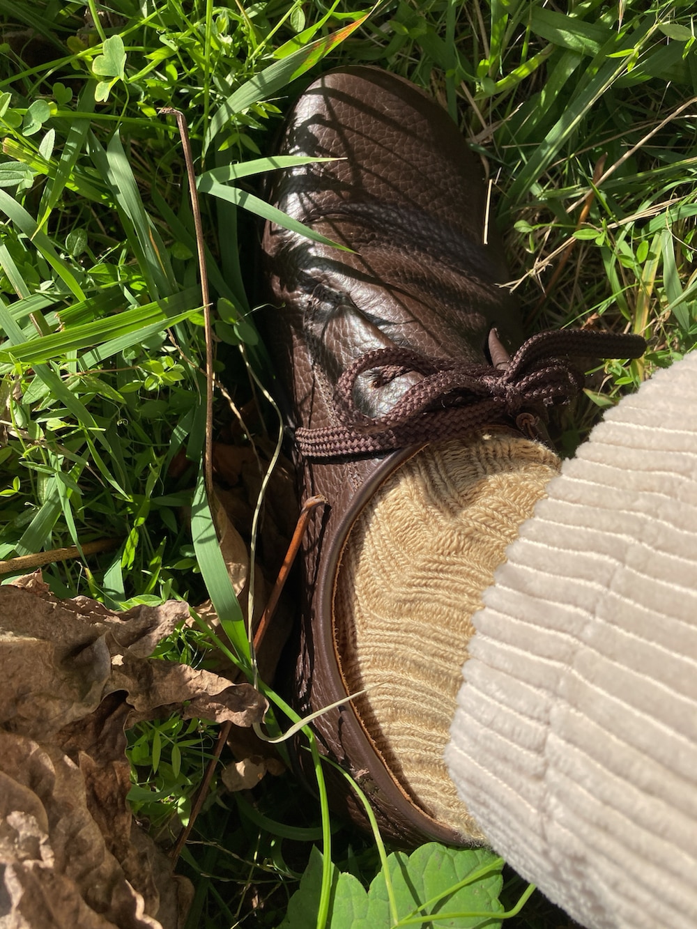 ブラウン系のライダースジャケット、ベージュ系のニット/セーター、ホワイト系のパンツを着用したメンズの秋コーディネートの3枚目の写真