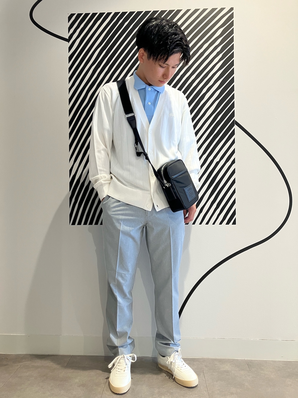 グレー系のチノパンツ、ブラック系のショルダーバッグ、ブルー系のポロシャツを着用したメンズの夏コーディネートの2枚目の写真