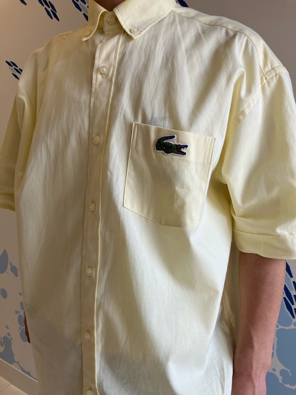 イエロー系のシャツ/ブラウス、ホワイト系のスニーカー、ブルー系のチノパンツを着用したメンズの夏コーディネートの4枚目の写真