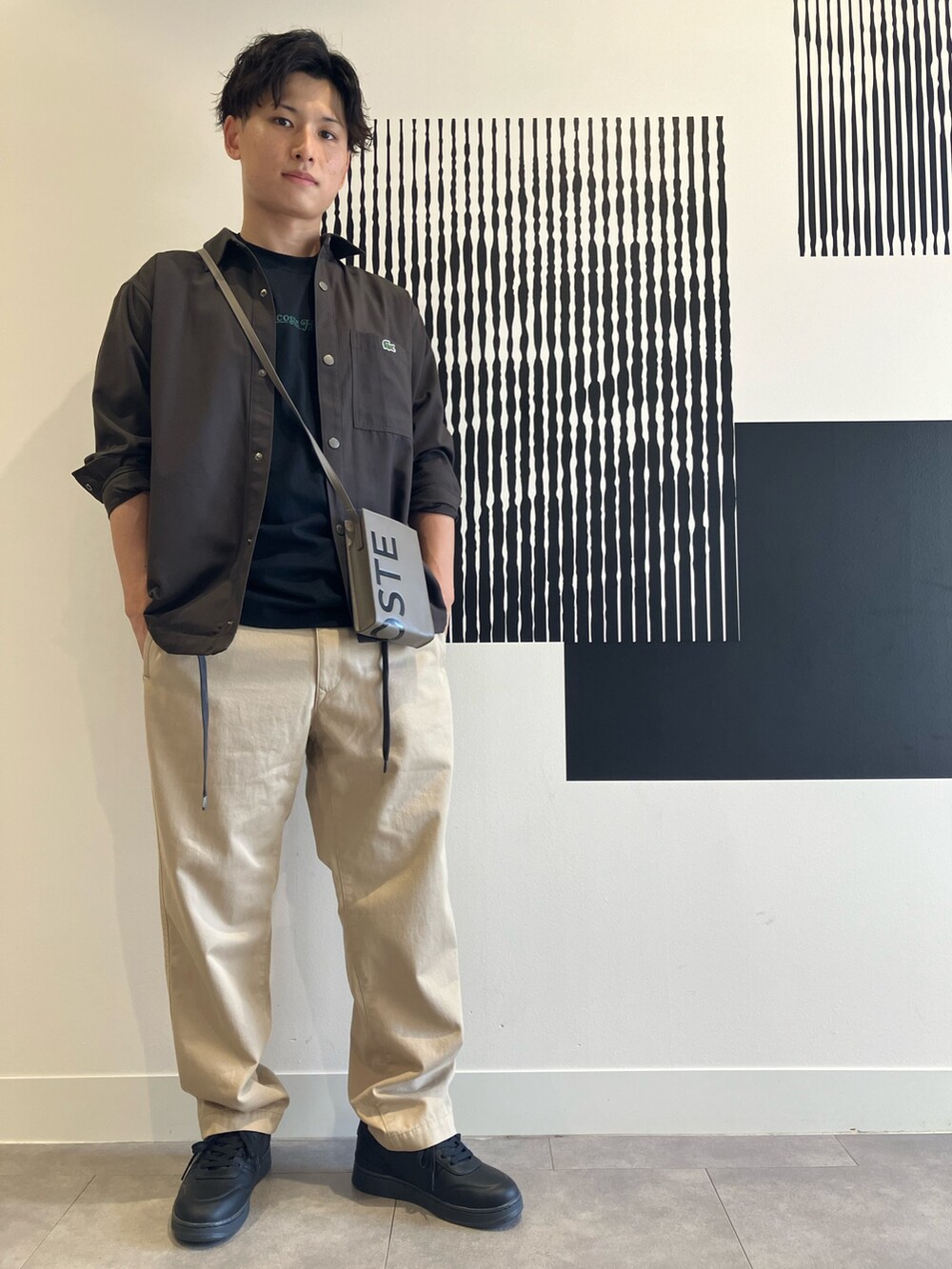 ブラック系のTシャツ/カットソー、ベージュ系のチノパンツ、ブラック系のスニーカーを着用したメンズの秋コーディネートの3枚目の写真