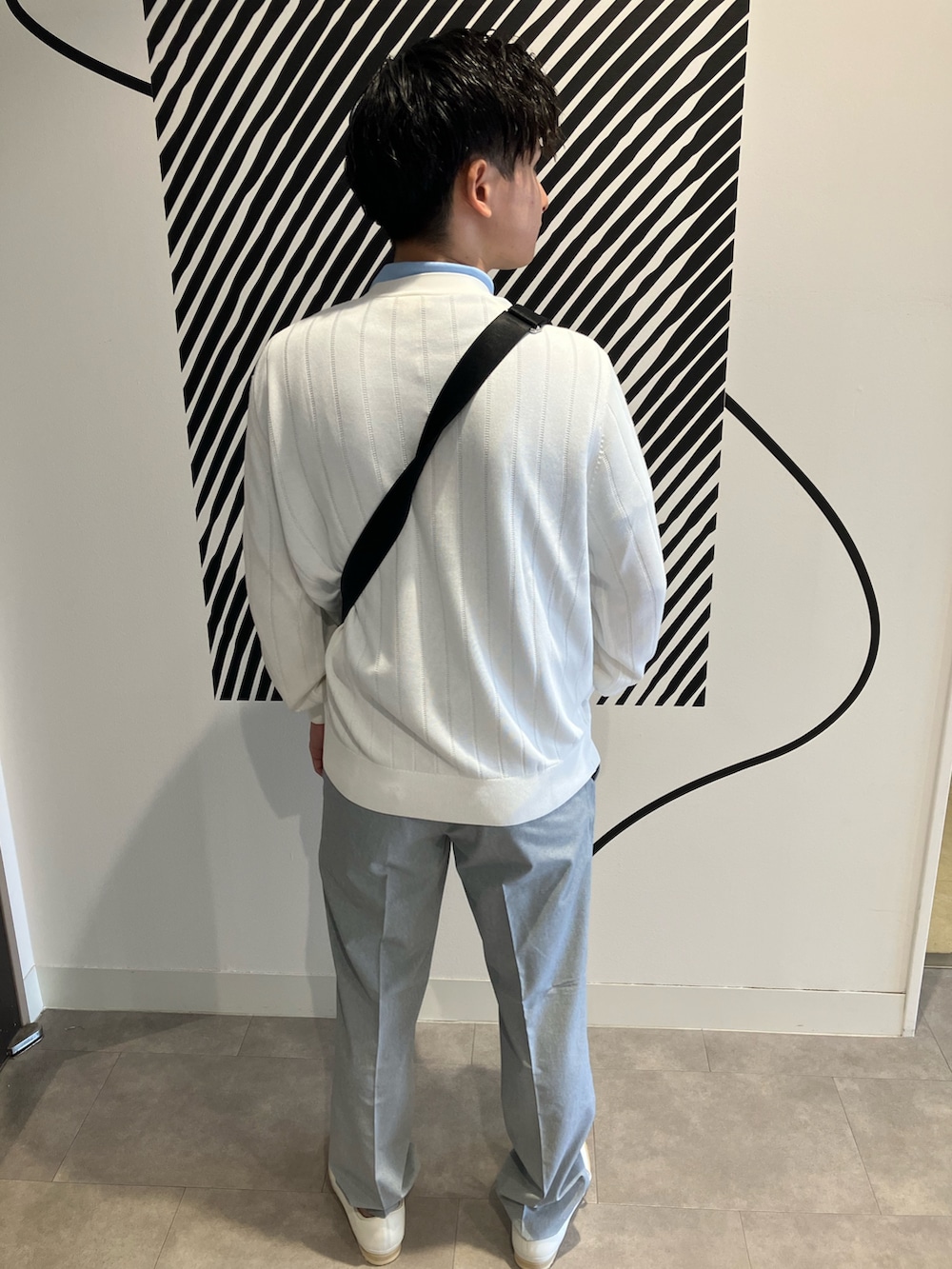 グレー系のチノパンツ、ブラック系のショルダーバッグ、ブルー系のポロシャツを着用したメンズの夏コーディネートの4枚目の写真