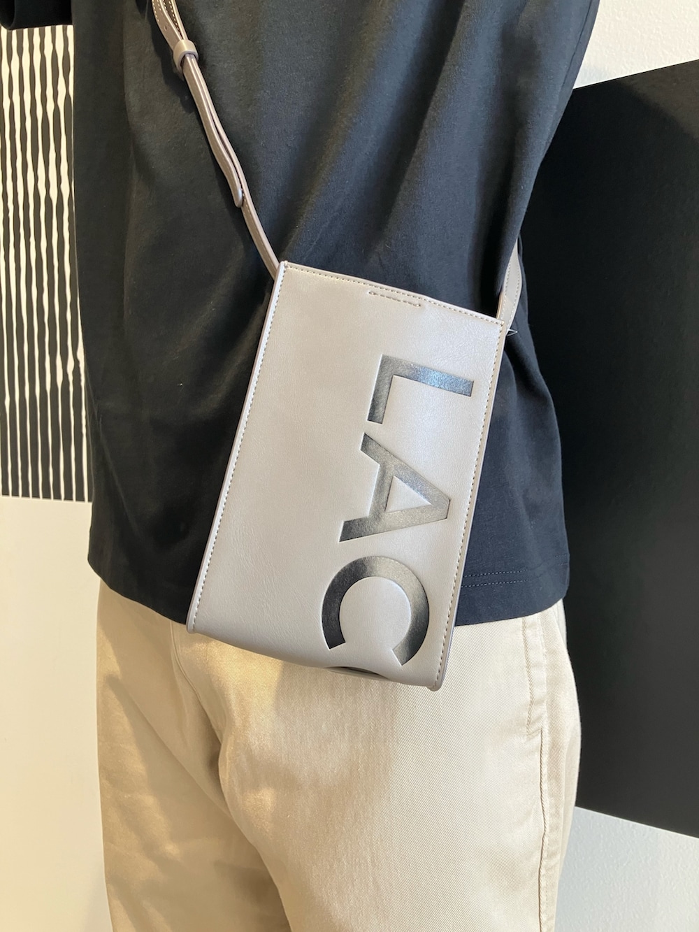 ブラック系のTシャツ/カットソー、ベージュ系のチノパンツ、ブラック系のスニーカーを着用したメンズの秋コーディネートの5枚目の写真