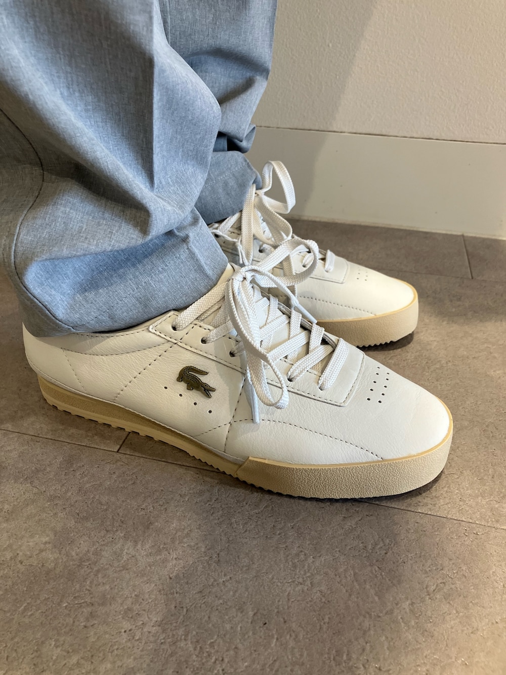 グレー系のチノパンツ、ブラック系のショルダーバッグ、ブルー系のポロシャツを着用したメンズの夏コーディネートの6枚目の写真