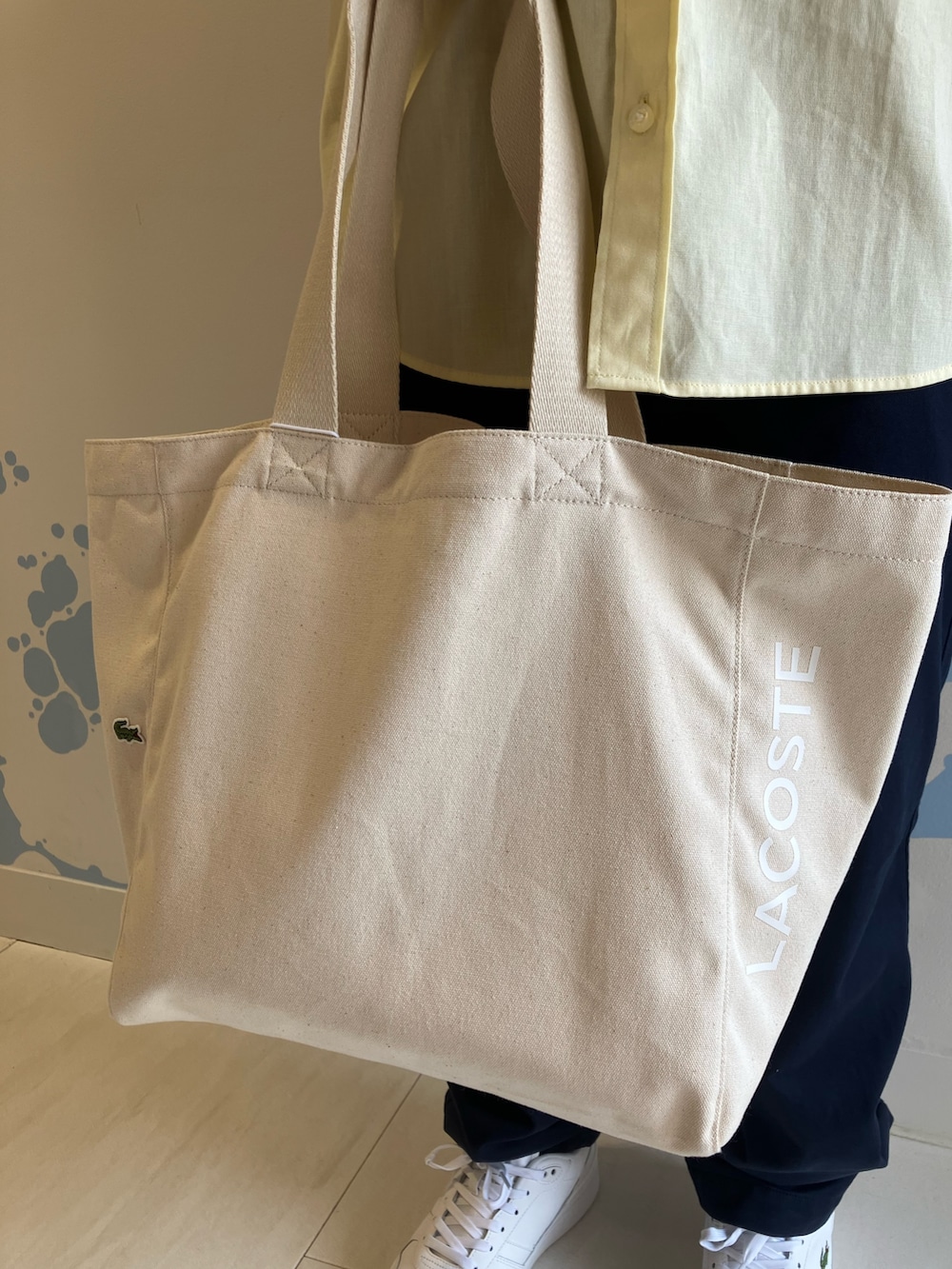 イエロー系のシャツ/ブラウス、ホワイト系のスニーカー、ブルー系のチノパンツを着用したメンズの夏コーディネートの5枚目の写真