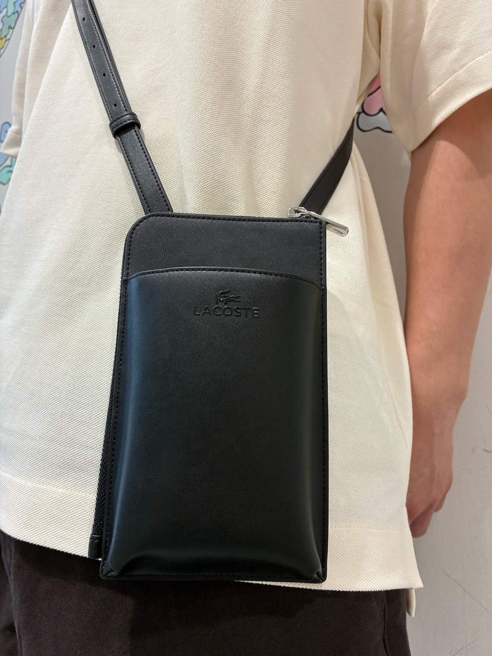 ブラック系のショルダーバッグ、ホワイト系のポロシャツ、ブラウン系のその他パンツを着用したメンズの夏コーディネートの4枚目の写真