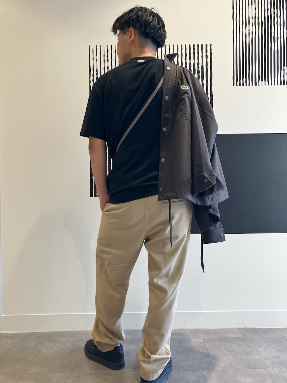 ブラック系のTシャツ/カットソー、ベージュ系のチノパンツ、ブラック系のスニーカーを着用したメンズの秋コーディネートの4枚目の写真