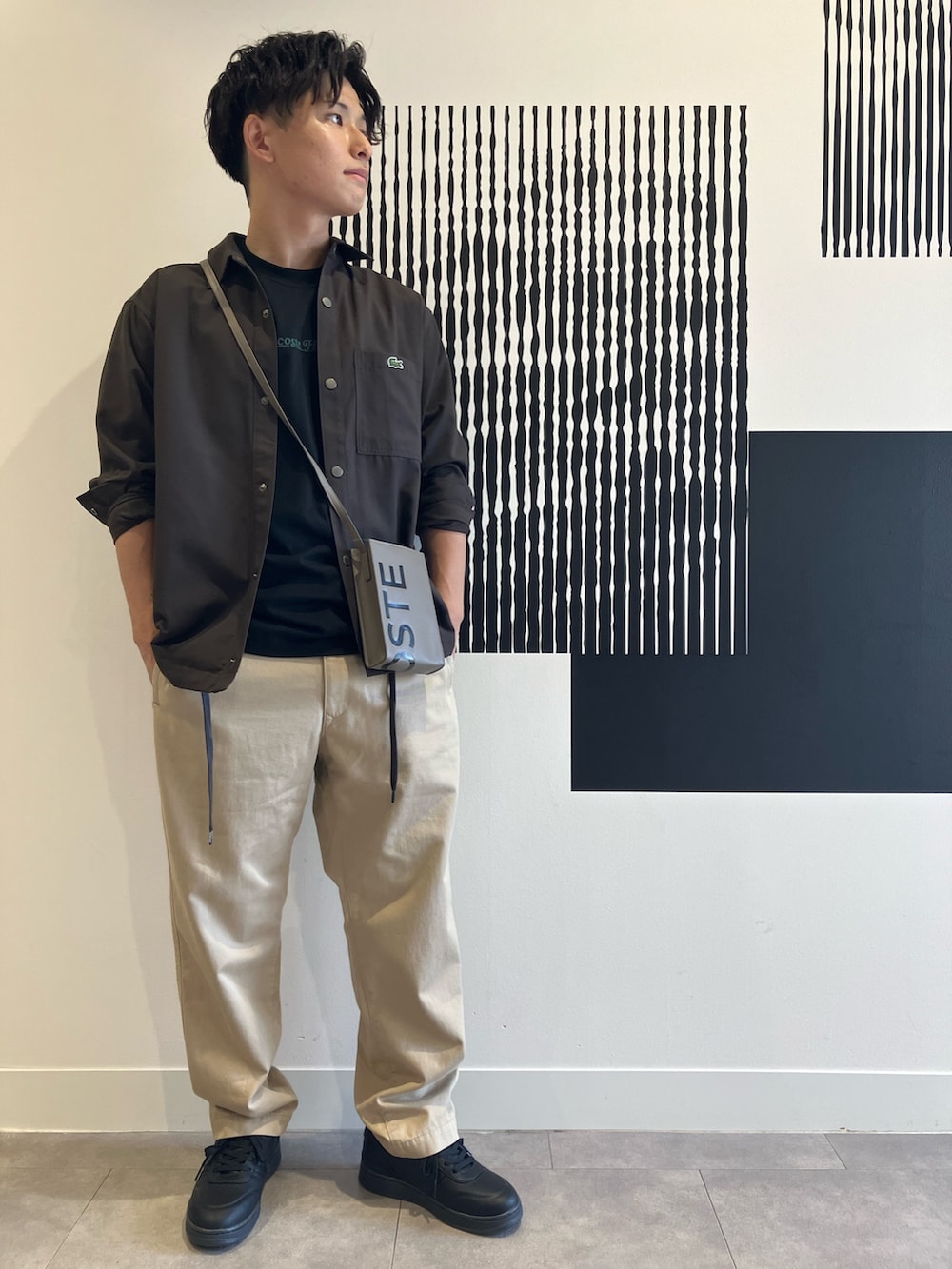 ブラック系のTシャツ/カットソー、ベージュ系のチノパンツ、ブラック系のスニーカーを着用したメンズの秋コーディネートの2枚目の写真