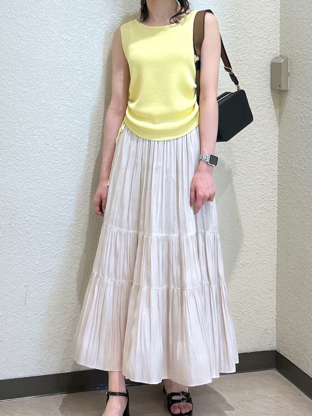 イエロー系のニット/セーター、ホワイト系のスカート、ブラック系のサンダルを着用したレディースの夏コーディネートの4枚目の写真