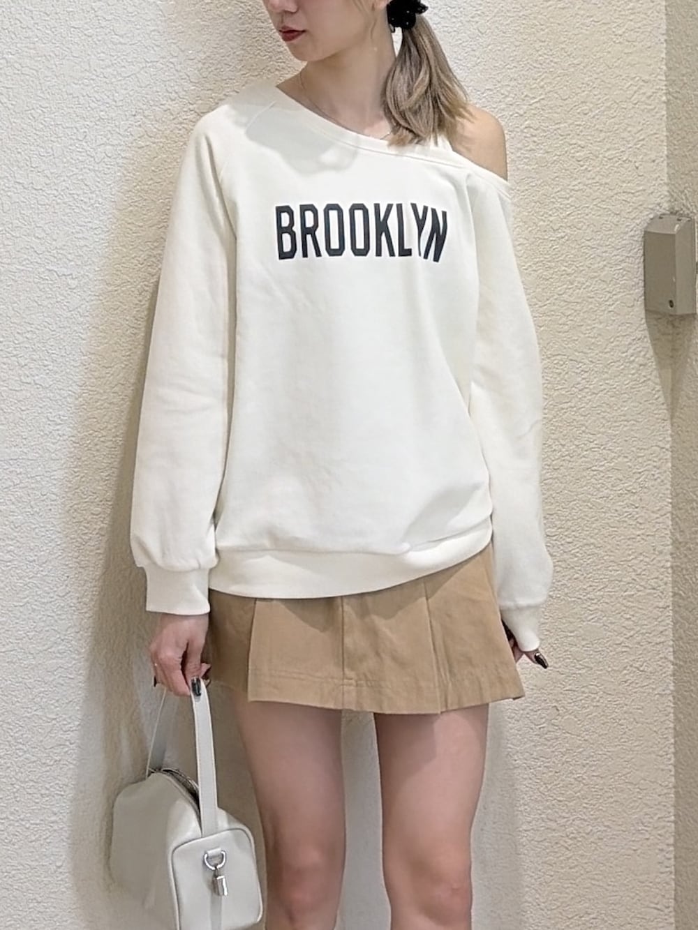 ホワイト系のスウェット、ベージュ系のスカート、ブラック系のローファーを着用したレディースの春コーディネートの3枚目の写真